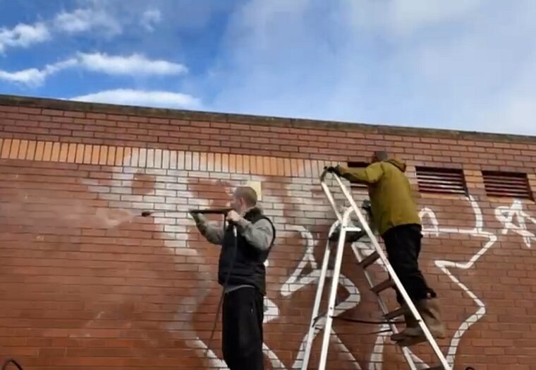 Team removing graffiti from a wall
